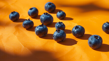 Fresh blueberries on orange background, captured in a minimal concept photography style.Soft light and high key lighting create a tranquil atmosphere, complemented by the vibrant orange color palette