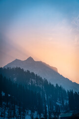 Winter mountain sunset scenery shot from Kashmir, Beautiful Snow covered mountain view with pine trees during sunset