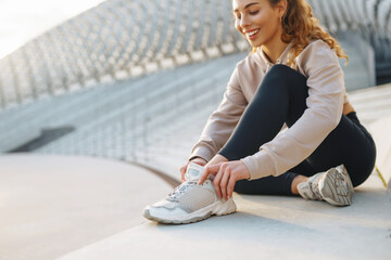 Smiling woman stretching her legs before jogging outdoors in the morning. Sport, gym and healthy...