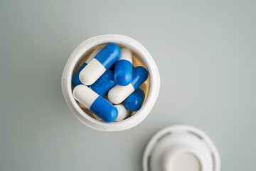 Blue and white capsules in a jar close-up.