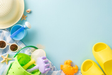 Colorful summer beach holiday set up with a selection of children's toys, sunglasses, hat, and starfish on a soft blue background
