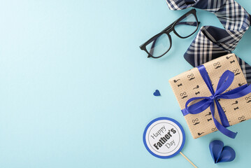 A Father's Day themed flat lay with a gift box, striped tie, glasses, and a Happy Father's Day label on a pastel blue background