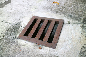 an iron gutter cover, with a rust color. Box shaped. on a concrete road