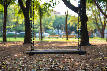 Childrens swing on playground in park with trees