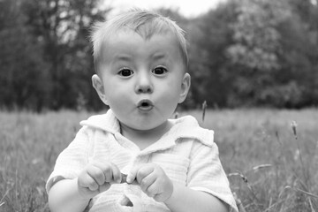 Portrait of a little boy in the field surprised and with his mouth open, black and white photo