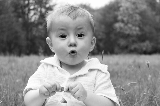 Fototapeta Portrait of a little boy in the field surprised and with his mouth open, black and white photo