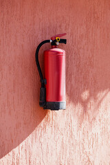 Fire extinguisher on the terracotta exterior wall of the house