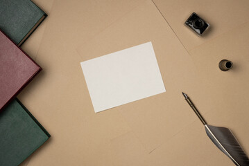 Empty white paper list with quill pen, ink and books on sheets of paper background from above. Vintage. Copy space