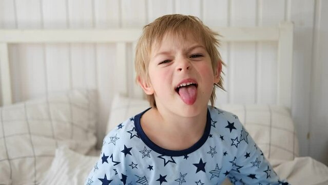 Boy joking, sticking tongue out with silly expression. Child making face. Funny foolishness portrait of little baby boy on white background. Adorable Caucasian kid making crazy and comical gesture.