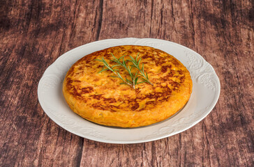 Potato and onion omelet on a white plate on a rustic table