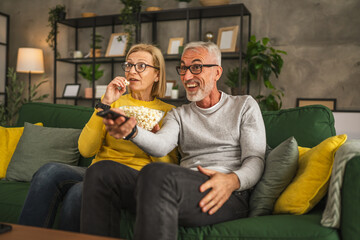 Mature senior couple husband and wife watch movie and eat popcorn