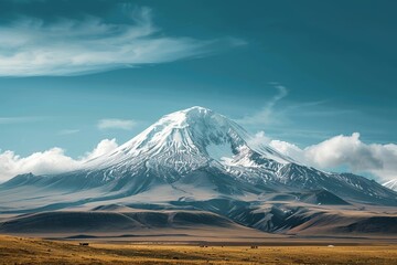 Fototapeta premium A large snow covered mountain stands tall in the middle of a field, A majestic snow-capped mountain rising in the distance