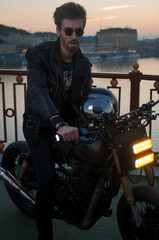 handsome man on a motorcycle against the background of the sunset in the city