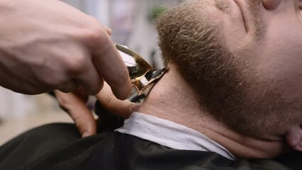 Hairdresser uses trimmer cutting client beard in barbershop closeup. Skilled barber does facial haircut with tool in men beauty salon