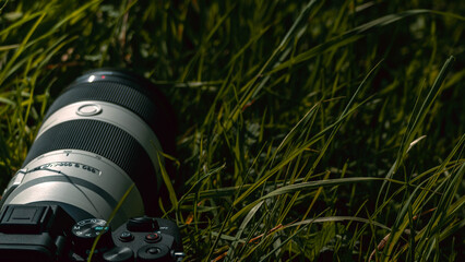 A closeup shot of a professional DSLR camera in the grass.