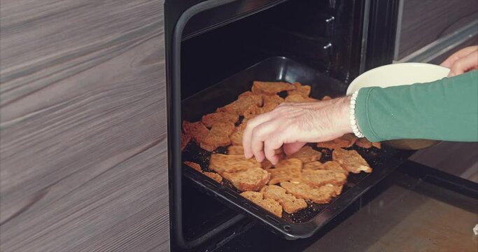 A man takes baked crackers from a buckwheat baguette out of the oven in the kitchen
