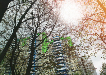 Light coming through spring trees covering green and blue building