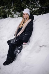 Portrait of a teenage girl sitting in a snowdrift in winter.