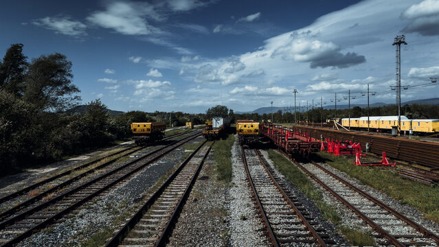 Railway tracks in the countryside with blue sky and white clouds.