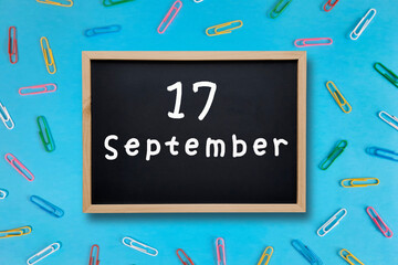 September 17 written in chalk on black board. Calendar date 17th of September on chalkboard on blue...