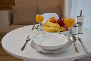 Table set with dishware, fruit bowl, and utensils for a meal