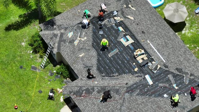 Construction workers installing asphalt shingles as house roof covering. Building of Florida home rooftop. Real estate development concept