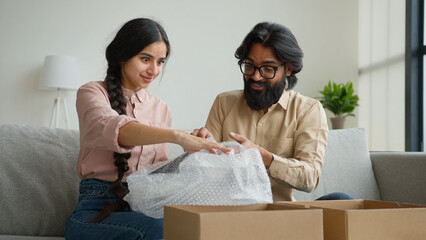 Happy couple customers receive parcel look inside box Arabian Indian man and woman open delivery...
