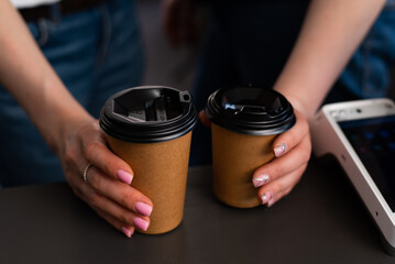 Cups of coffee with black lids in women's hands. Coffee cups