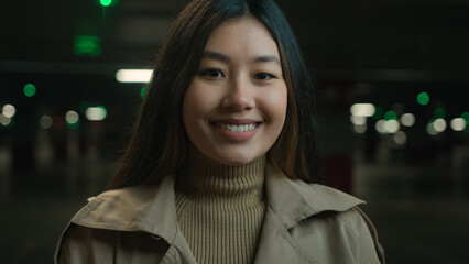 Asian funny happy ethnic 20s woman joyful pretty girl looking at camera laughing in dark night parking lot young chinese korean japanese Asia lady having fun laugh laughter cheerful smile dental care