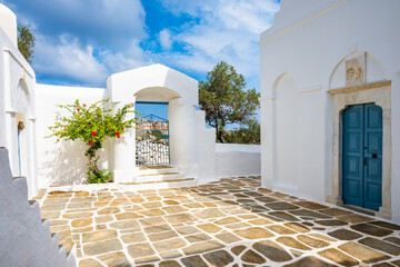 Courtyard of traditional style white church Panagia Poulati with blue dome on sea coast near Kastro...