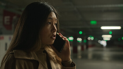 Worried upset Asian woman talk mobile phone in parking call worried talking disappointed smartphone...