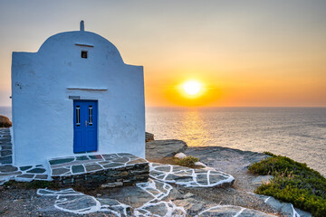 Sunrise over blue sea and small church built on rocky coast in Kastro village, Sifnos island, Greece
