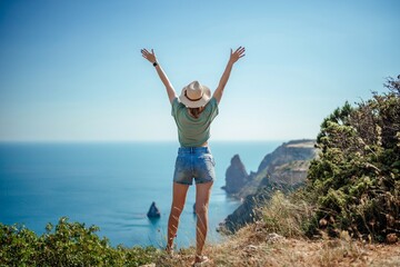 Woman tourist sky sea. Happy traveller woman in hat enjoys vacation raised her hands up