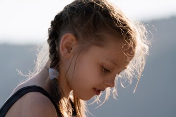 A young girl with braided hair is looking at the camera. She has a red lip and her hair is wet.