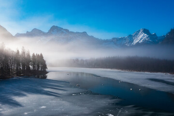 Misty Winter Morning at Almsee in Upper Austria, Serene Frozen Lake Surrounded by Snowy Alpine Peaks