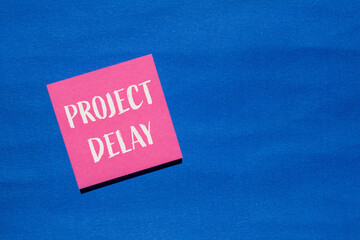 Project delay words written on pink paper sticker with blue background. Conceptual project delay...