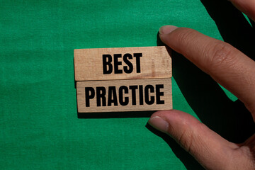 Best practice words written on wooden blocks with green background. Conceptual best practice...
