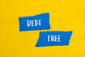 Debt free words written on ripped blue paper pieces with yellow background. Conceptual debt free...