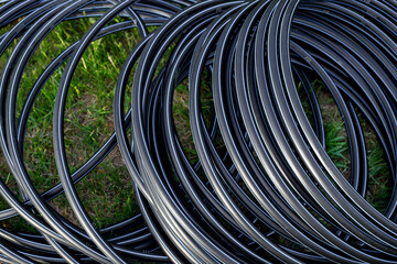 Black HDPE pipe for water supply, wound into a roll. Installation of water supply and drip irrigation in the garden