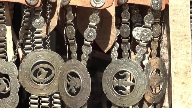 Handmade Argentine gaucho belt. Metal gaucho harrows carved with horse and religious motifs. Traditional accessory of the Argentine gaucho's clothing. Traditional crafts fair.