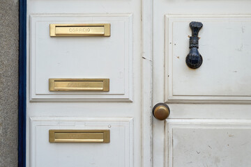 Letter box aka letterbox, letter plate, letter hole, mail slot, or mailbox. Old white vintage door with a knocker in Portugal.