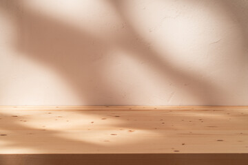 Empty table on neutral color background with natural shadows on stucco wall. Mock up for branding...