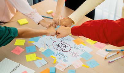Young happy creative startup group join circle fist bump hands together surrounded by marketing...