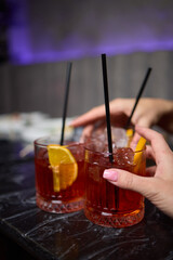 A woman holds a cocktail in her hand, with her fingers wrapped around the glass