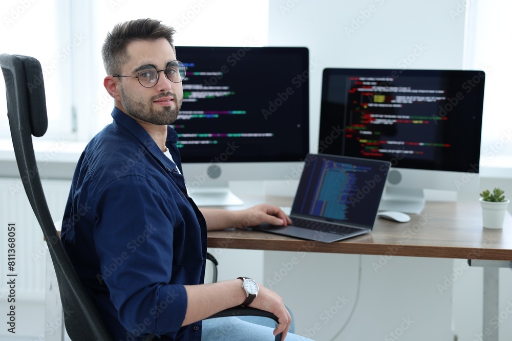 Poster young programmer working at desk in office
