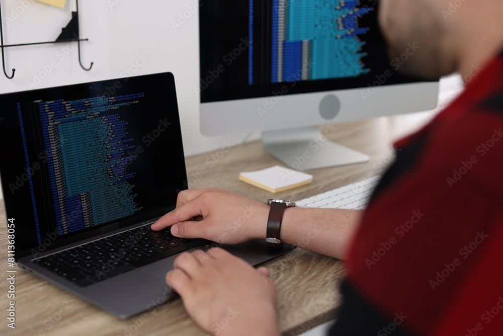 Poster programmer working with laptop at desk in office, closeup