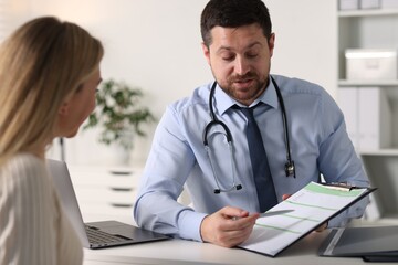 Professional doctor working with patient at white table in hospital