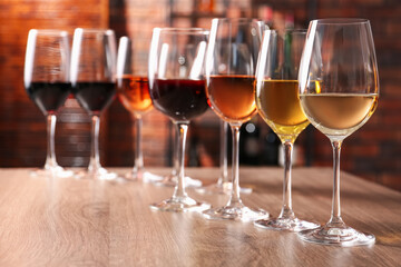 Different tasty wines in glasses on wooden table, space for text