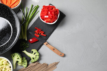 Wok pan, noodles and other products on light grey table, flat lay. Space for text