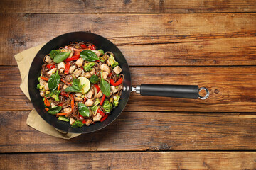 Stir-fry. Tasty noodles with meat and vegetables in wok on wooden table, top view